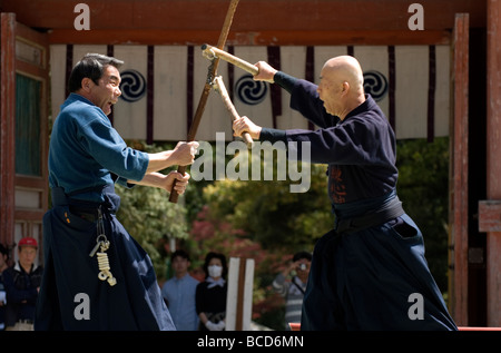 Due uomini si impegnano in una lotta riscaldato utilizzando le tradizionali armi giapponesi come nunchaku e bastone di legno Foto Stock