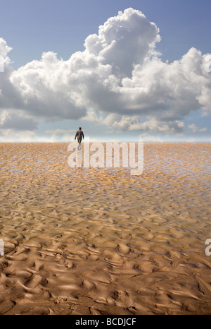 Un uomo che cammina su una spiaggia in un lontano orizzonte Foto Stock