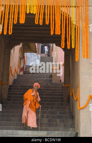 Un vecchio sacerdote (bramino) scendendo una scala vicino al fiume Gange (bagno ghats) di Varanasi (India). La festa di Diwali 2008. Foto Stock