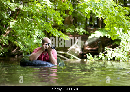 Uomo di fotografare dall'acqua in un innertube Foto Stock