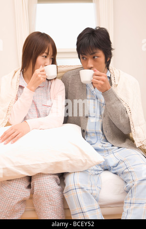 Coppia giovane di bere il caffè sul letto Foto Stock