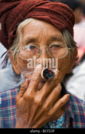 Myanmar. La Birmania. Nyaung U. Una vecchia donna bespectacled fuma un locale in cheroot Nyaung U mercato. Foto Stock