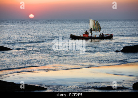 Myanmar Birmania, Stato di Rakhine. L'equipaggio di una barca da pesca hurries home di Sittwe come il sole tramonta sulla Baia del Bengala. Foto Stock