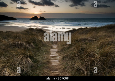 Sole che tramonta dietro Gull Rock sulla spiaggia di Holywell North Cornwall Foto Stock