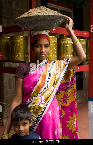 Donna indiana che trasportano materiali edili in un cestello sul suo capo a Norbulingka Istituto. Sidhpur, Dharamsala. HP. India. Foto Stock