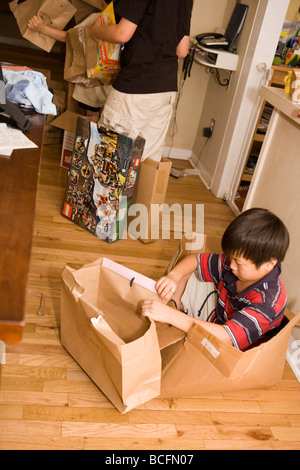 Bambino di nove anni e gli amici creando forti e costumi di scartare le scatole di cartone Foto Stock