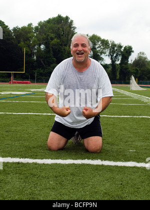 Il sovrappeso medioevo senior stretching uomo i suoi muscoli fitness uno stile di vita sano immagine dopo che esercitano sul campo sportivo Foto Stock