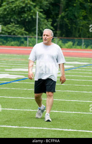 Il sovrappeso medioevo senior uomo esercita sul campo sportivo Foto Stock