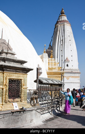 Kathmandu, Nepal. Il nepalese adoratore la filatura Ruote della preghiera a Swayambhunath Temple. Lo zafferano macchie di acqua lo stupa dome. Foto Stock