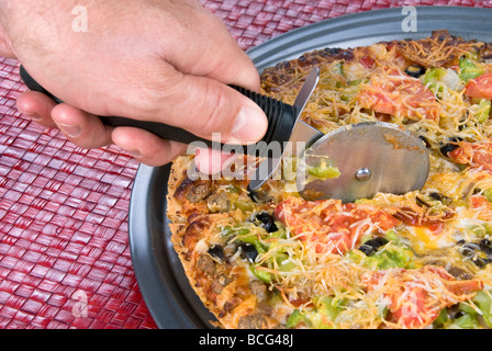 Un caldo tutte le opere la pizza viene affettato con un forte tagliapizza Foto Stock