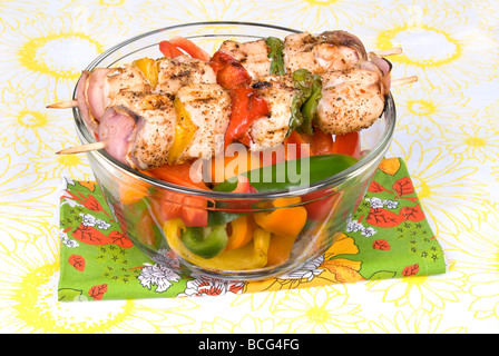 Appena cucinato spiedini di pollo kebobs con i peperoni e le cipolle su una ciotola di freschi peperoni per snacking Foto Stock