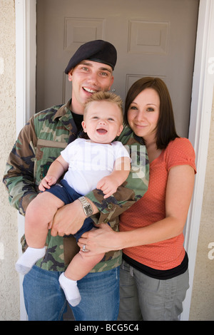 Giovane famiglia militare in piedi di fronte alla loro casa con il bimbo di un anno. Foto Stock