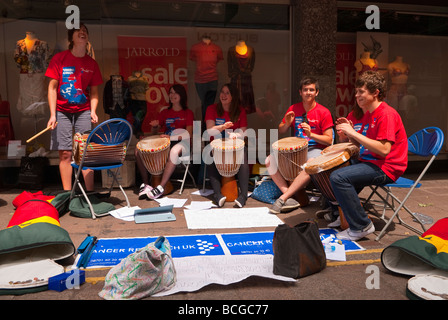 Buskers musicali con i tamburi africani musicista di strada in aiuto del Cancer Research UK in Norwich Norfolk Regno Unito Foto Stock