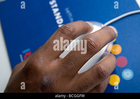 La mano di un maschio nero utilizzando un Mac apple mouse per navigare e utilizzare un computer Foto Stock