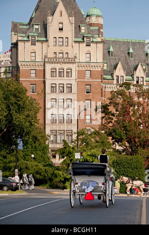 Su una bella giornata d'estate un cavallo e carrozza porta i turisti intorno a Victoria, B.C. La Empress Hotel è in background. Foto Stock