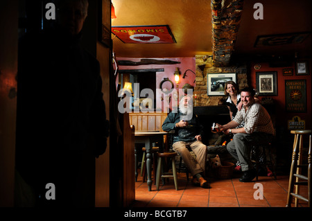 Gruppo mediante un fuoco aperto in un pub tradizionale con un cliente nel portale GLOUCESTERSHIRE England Regno Unito Foto Stock