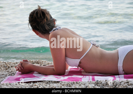 Giovane donna sdraiata sulla spiaggia da ocean Foto Stock