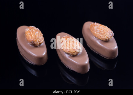 Tre mandorla cioccolatini disposti su sfondo scuro Foto Stock