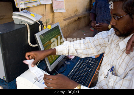 Un uomo si siede da un computer in una strada in India. Egli controlla online i biglietti della lotteria di Mysore. Foto Stock