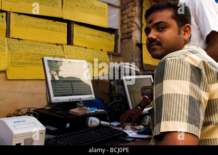 Un uomo si siede da un computer in una strada in India. Egli controlla online i biglietti della lotteria di Mysore. Foto Stock