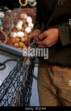 Fishermans commerciale mani come egli le riparazioni seine net in preparazione per la pesca Whittier Alaska molla Foto Stock