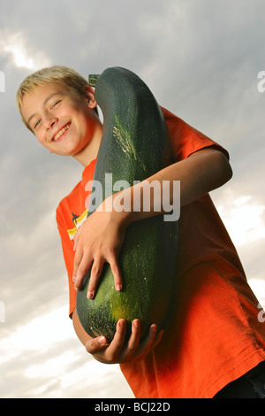 Ritratto di un giovane ragazzo in azienda una grande zucchini in Alaska State Fair Foto Stock