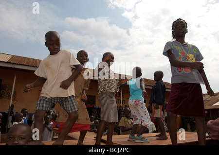 I bambini danza sulla scrivania al di fuori della scuola nella baraccopoli di Kampala Foto Stock