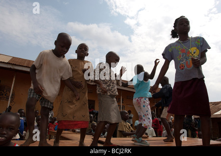 I bambini danza sulla scrivania al di fuori della scuola nella baraccopoli di Kampala Foto Stock