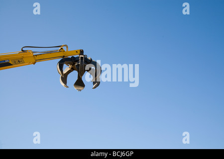 Artiglio del giallo macchina meccanico utilizzato per il prelievo di rottami di metallo al cantiere reclycling contro il cielo blu Indio California USA Foto Stock