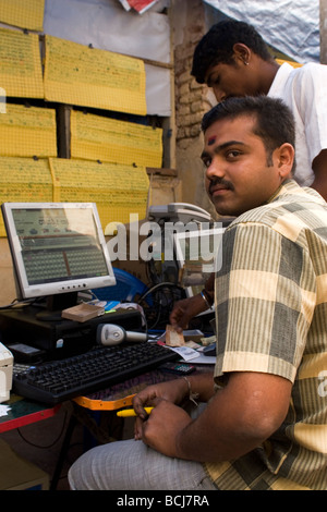 Un uomo si siede da un computer in una strada in India. Egli controlla online i biglietti della lotteria di Mysore. Foto Stock