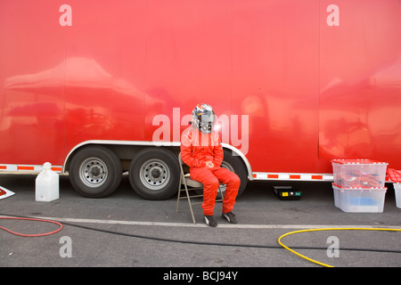 Race Driver auto indossando il casco e red jump suit seduto in poltrona di fronte a red veicolo di trasporto Foto Stock