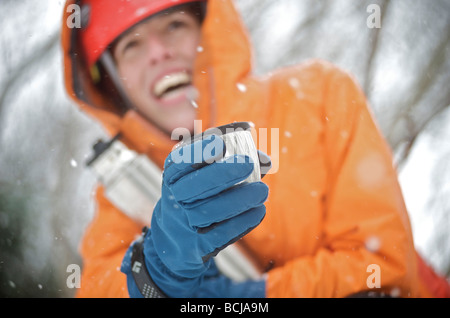 Femmina ice climber gode di una bevanda calda durante una giornata di arrampicata su ghiaccio nella valle di Portage, Alaska Foto Stock