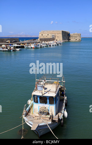 Un greco la pesca in barca al porto di Iraklion creta con l'epoca veneziana Koule fortezza in background Foto Stock