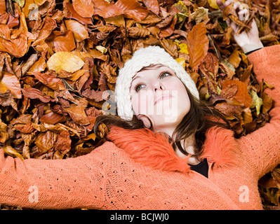 Donna sdraiata su foglie di autunno Foto Stock