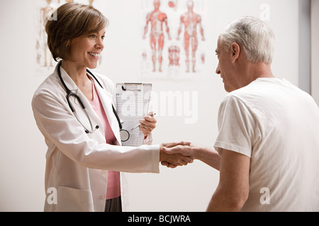 Medico stringono le mani con paziente Foto Stock