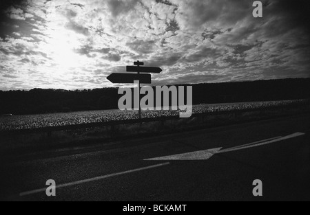 Segno posto sulla strada di fronte del cielo con le nuvole, b&W Foto Stock