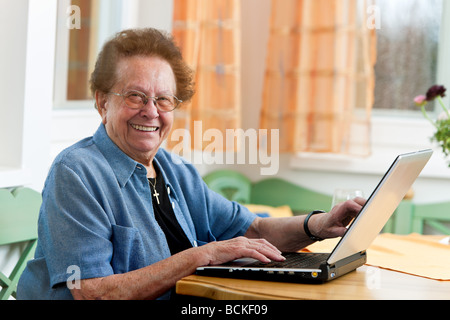 Vecchia donna con un computer portatile scrive e-mail Foto Stock