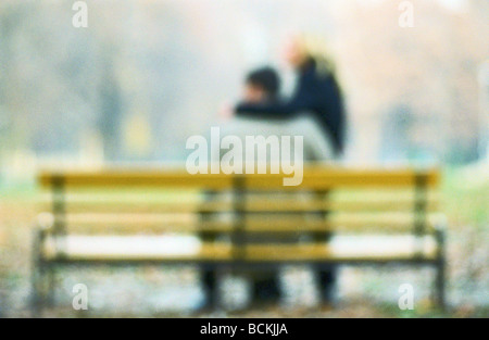 Giovane seduto su una panchina nel parco, offuscata Foto Stock