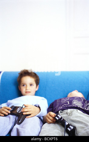 Due ragazzi seduti sul divano tenendo i joystick Foto Stock