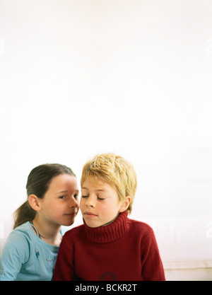 Ragazza whispering a seconda ragazza con gli occhi chiusi Foto Stock
