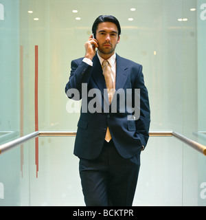 Imprenditore in piedi con il cellulare in ascensore Foto Stock