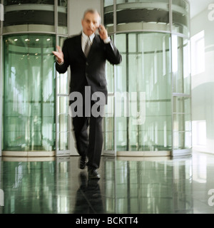 Uomo in ufficio lobby e camminare con il cellulare Foto Stock