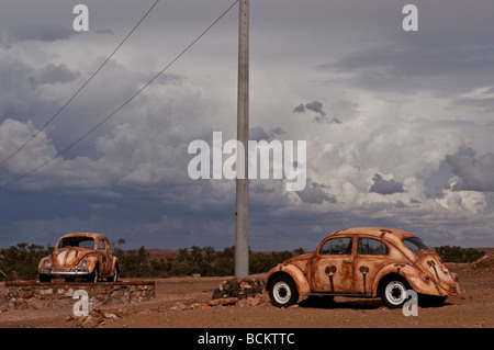 Due dipinti scarabeo di Volkswagen auto in un paesaggio deserto di Silverton NSW Australia Foto Stock