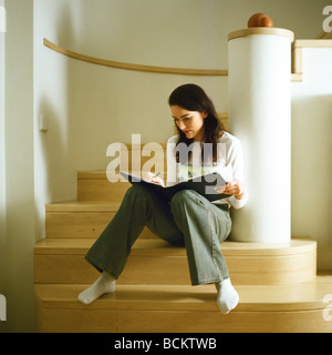 Donna seduta sui gradini con file, scrittura Foto Stock