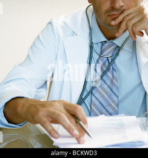 Medico che indossa lo stetoscopio e tenendo la penna, vista parziale Foto Stock