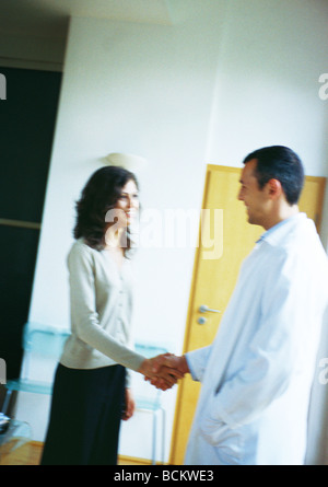 Medico e donna stringono le mani, smliling Foto Stock