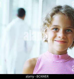 Ragazza sorridente, medico a piedi in background Foto Stock