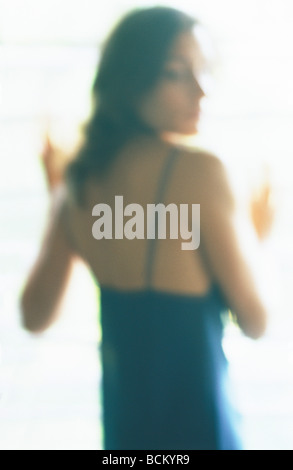 Donna in abito guardando sopra la spalla, sfocato Foto Stock