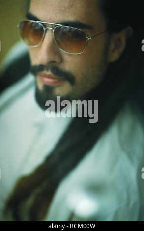 Uomo con dreadlocks indossando occhiali da sole, ritratto Foto Stock