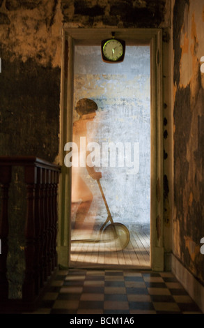 Equitazione donna scooter su pavimento in legno duro, visto attraverso la porta, movimento sfocato Foto Stock